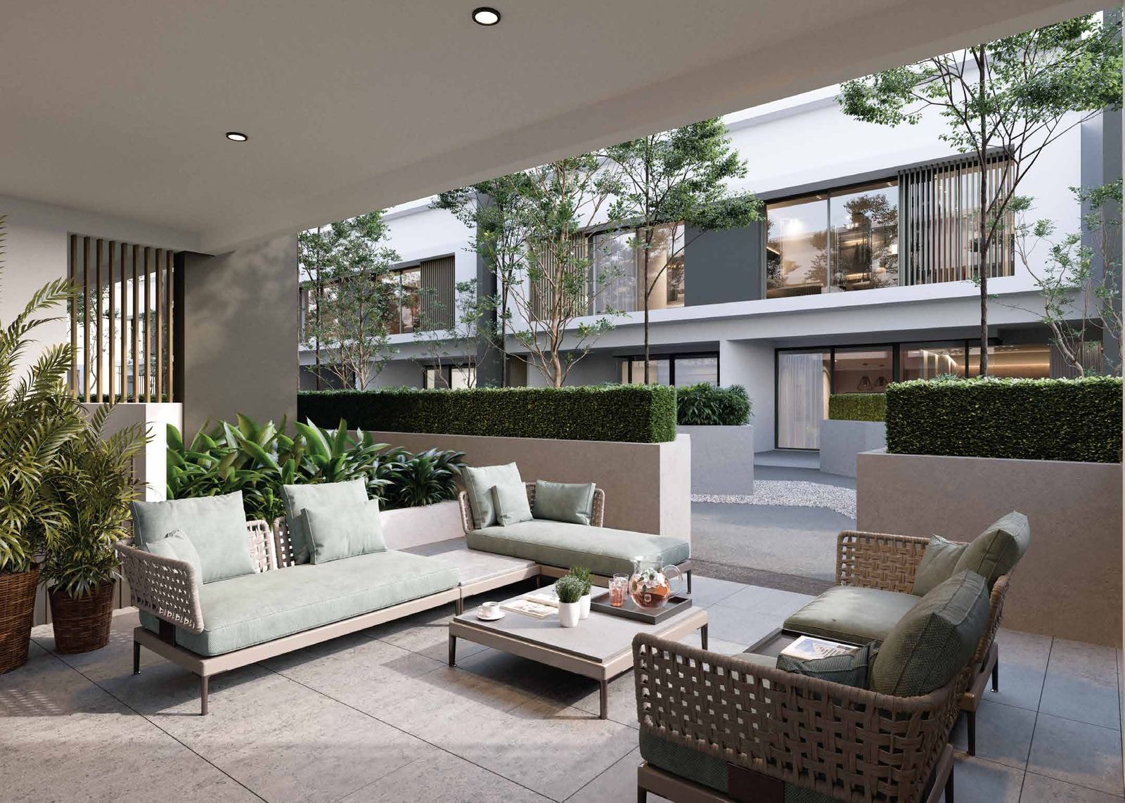 Outdoor lounge seating area with woven furniture surrounded by manicured hedges and townhouse balconies